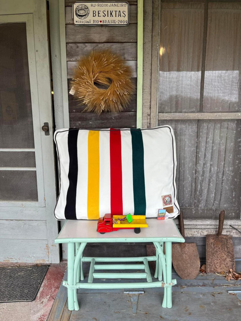 Pendleton dog bed and antique toy truck sitting on vintage table.